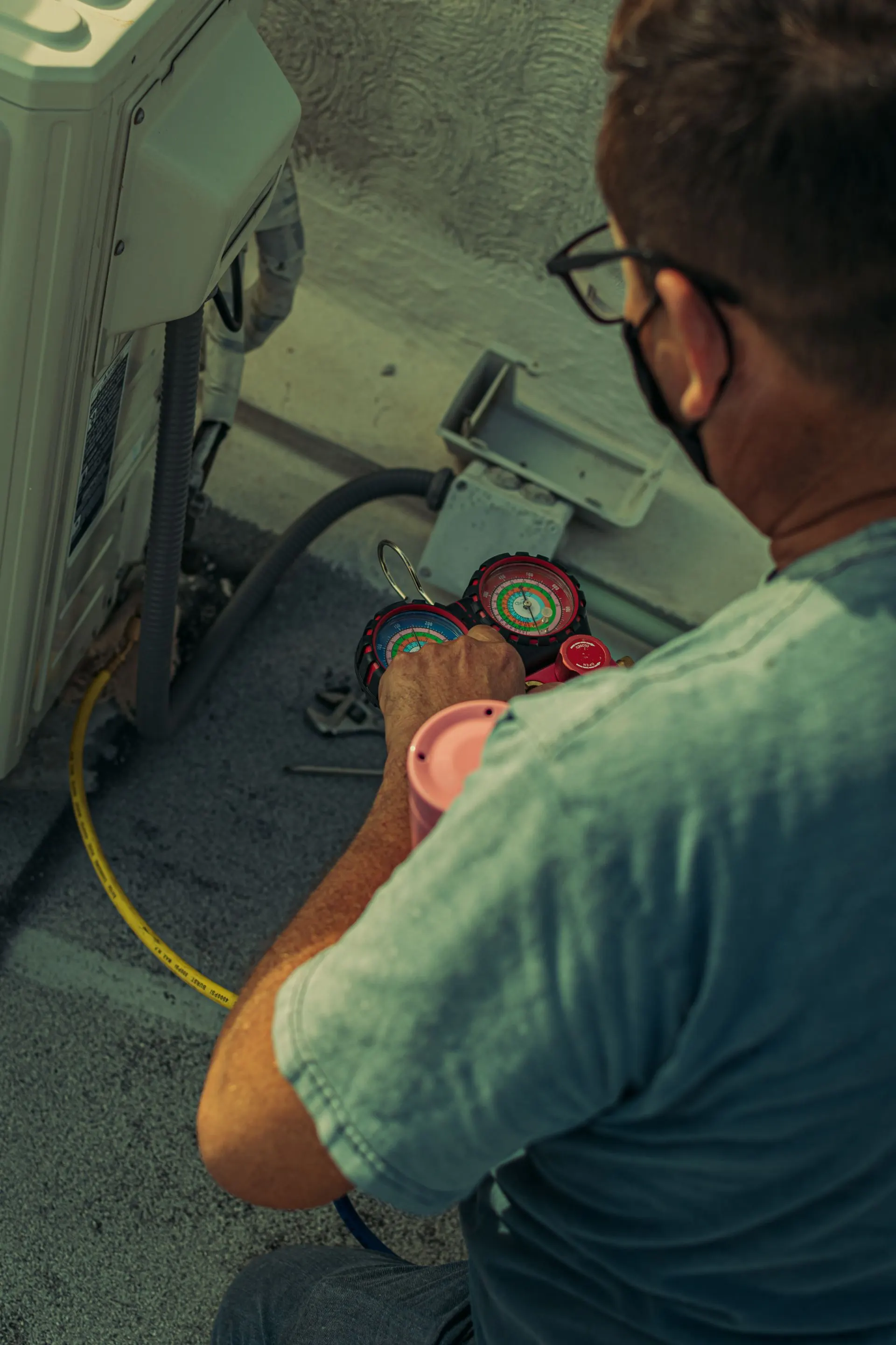 HVAC technician checking an outdoor AC unit with gauges
