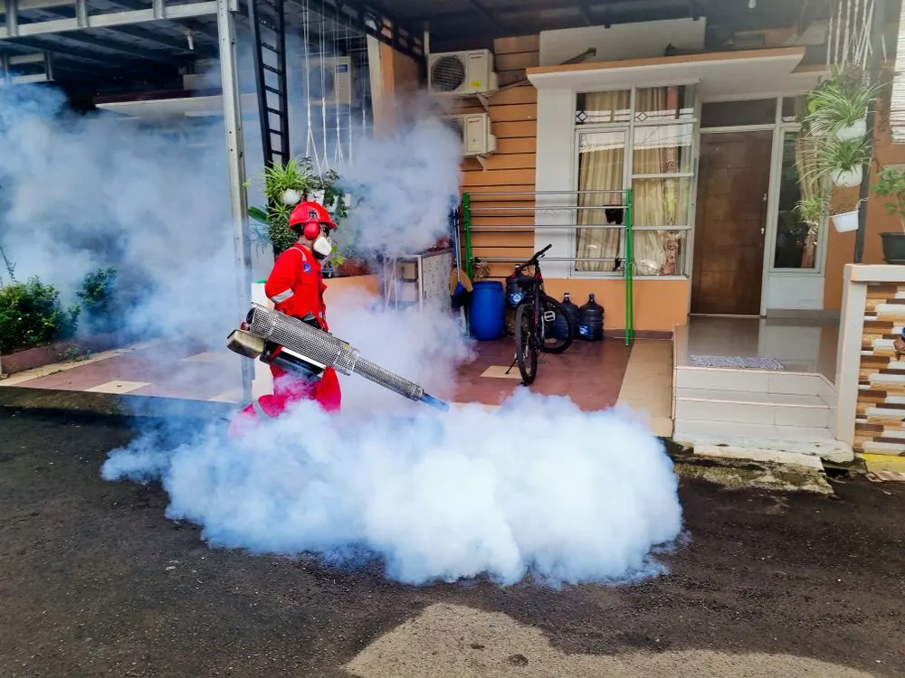 Pest control technician treating the outside of a house