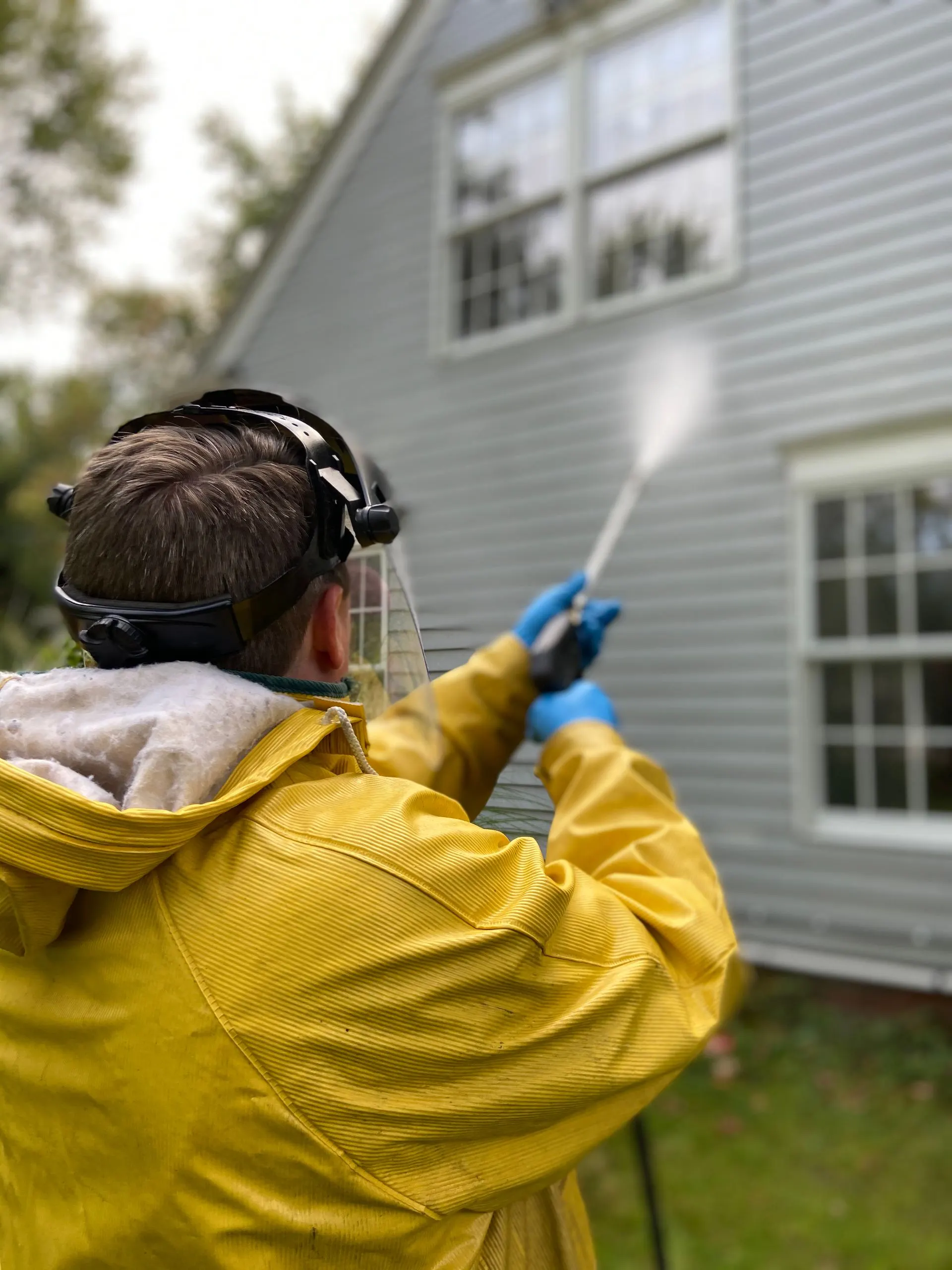 Worker pressure washing house siding